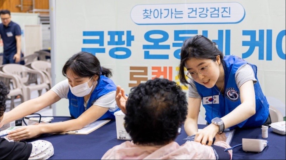 해남 ‘쿠팡 온동네 케어’ 검진 부스에서 파란 조끼를 입은 봉사자가 어르신의 혈압을 재는 모습