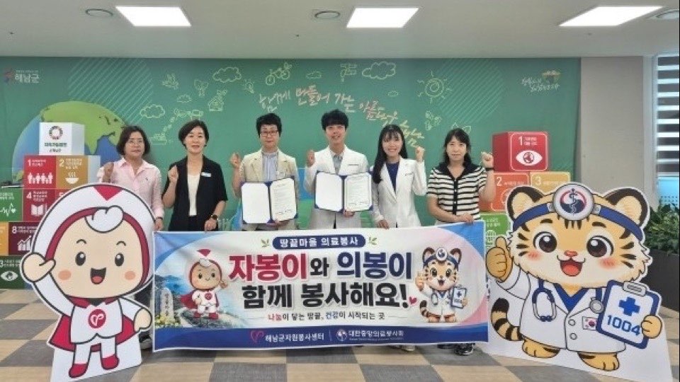 해남군자원봉사센터 협약식에서 관계자들이 협약서와 ‘자봉이와 의봉이 함께 봉사해요!’ 현수막을 들고 선 모습