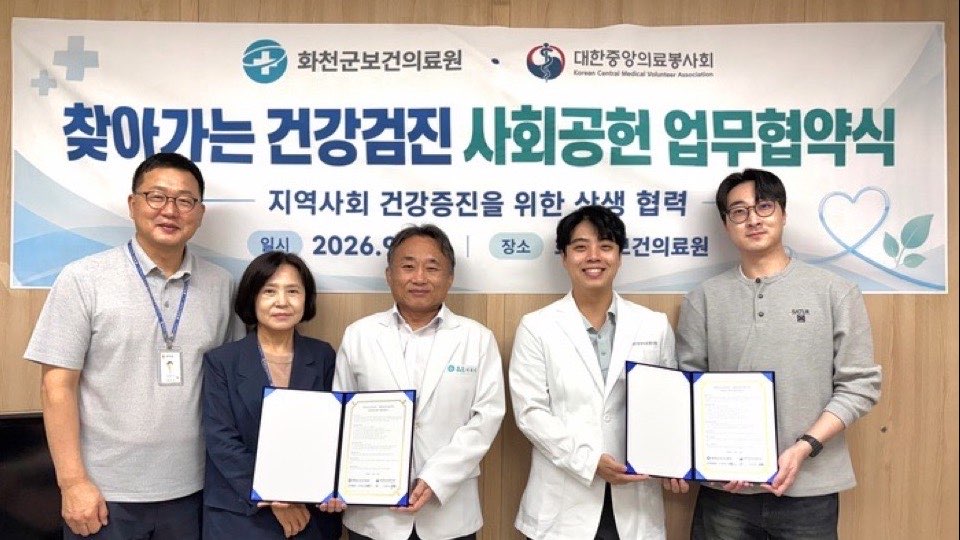 ‘찾아가는 건강검진 사회공헌 업무협약식’ 현수막 앞에서 화천군보건의료원과 봉사회 관계자들이 협약서를 들고 선 모습