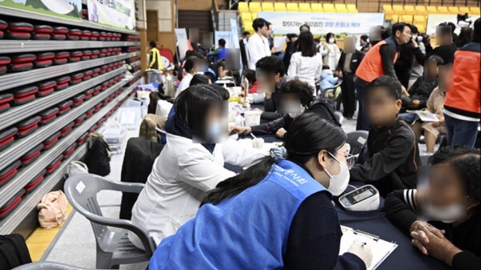 장수군 한누리전당 진료 현장에서 의료진과 봉사자가 주민들의 혈압을 재고 상담하는 모습