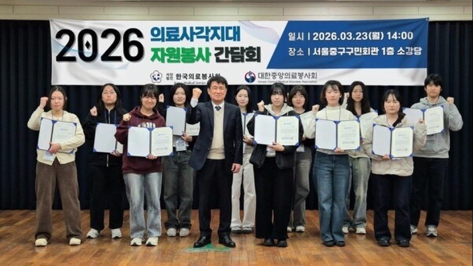 ‘2026 의료사각지대 자원봉사 간담회’ 현수막 앞 무대에서 대학생 참가자들이 수료증을 들고 기념촬영하는 모습